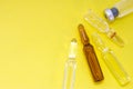 Glass vials with medications and drugs are on yellow uniform background view from above with clear area of half photo for labels,