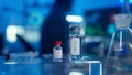 Glass vials with a vaccine and a syringe on a blurred laboratory background in blue light. Bottles with transparent Royalty Free Stock Photo