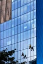 Glass wall cleaners hanging by surface of Q22 office tower of Echo Investment at al. Jana Pawla II avenue in Warsaw, Poland