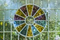 A glass wall of a greenhouse with a window of multi-colored glass