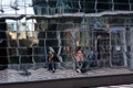 In the glass wall of a modern shopping center, broken reflections of people Royalty Free Stock Photo