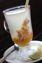 A glass of warm ginger drink and lime. Decorated with lemon grass in the glass.