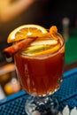 A glass of warming mulled wine decorated with a cinnamon stick and citrus.