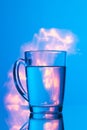 Glass of water on a blue background with a yellow abstraction, glare of light