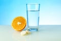 A glass of water, effervescent pill and orange on blue background with copy space. vitamin C concept. Royalty Free Stock Photo