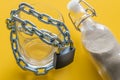 A glass of water entwined in a chain and closed with a padlock next to the sand-filled bottle. Global warming, a problem with drin