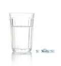 Glass with water and a heap of tablets, pills