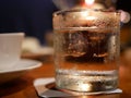 A glass of water with ice on a dinning table with candle light Royalty Free Stock Photo