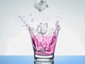 Glass of water that ice falls into the red fruit juice spread Royalty Free Stock Photo