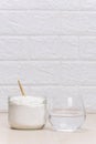 Glass of water and a jar of collagen goodnesson a marble beige background