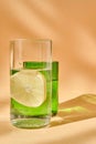 Glass of water with lemon and a green glass. Play of light