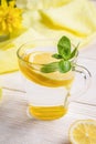 Glass of water with lemon and mint on light wooden table with yellow cloth. Royalty Free Stock Photo