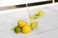 Glass of water with lemons, limes and mint on white wooden table outdoors Royalty Free Stock Photo
