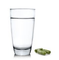Glass of water and moringa capsule pills on white background