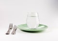 Glass of water in a plate with knife and fork isolated on white Royalty Free Stock Photo