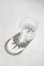 Glass of water and sharp hursh shadows stands on abright background. Drinking water concept Royalty Free Stock Photo