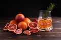 Glass with water and slices of blood orange and citrus fruits on a dark wooden background, functional water, healthy drink Royalty Free Stock Photo