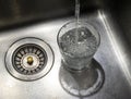 Glass of water in a steel sink Royalty Free Stock Photo