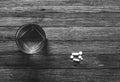 Glass of water tablets and capsules on wooden table top view, black and white photo