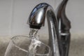 Glass at water tap and filling water with lead contamination Royalty Free Stock Photo