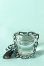 A glass of water wrapped in a chain and closed with a padlock. The concept of the problem of small drinking water resources in th