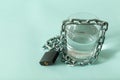 A glass of water wrapped in a chain and closed with a padlock. The concept of the problem of small drinking water resources in the