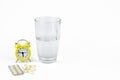 A glass of water, a yellow alarm clock and pills Royalty Free Stock Photo