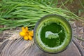 Glass of wheatgrass juice on a brown wooden table