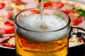 A glass in which beer is poured close-up on a background of pizza Royalty Free Stock Photo