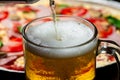 A glass in which beer is poured close-up on a background of pizza Royalty Free Stock Photo