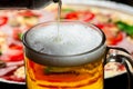 A glass in which beer is poured close-up on a background of pizza Royalty Free Stock Photo