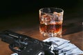 Glass of whiskey or cognac, gun, playing cards with money on the black mirror table. The concept of criminal. Royalty Free Stock Photo