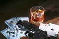 Glass of whiskey or cognac, gun, playing cards with money on the black mirror table. The concept of criminal. Royalty Free Stock Photo