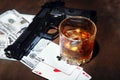 Glass of whiskey or cognac, gun, playing cards with money on the black mirror table. The concept of criminal. Royalty Free Stock Photo