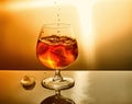 Glass of whiskey with drops and ice on an orange background Royalty Free Stock Photo