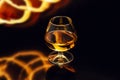 Glass with whiskey with fire and reflections on black background