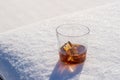 Glass of whiskey with ice on a bed of snow and white background  close up Royalty Free Stock Photo