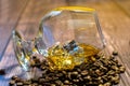 A glass of whiskey with ice and coffee beans on a wooden table. Strong alcohol with ice. Vintage close-up of golden cognac.