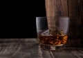 Glass of whiskey with ice cubes next to wooden barrel. Cognac brandy drink Royalty Free Stock Photo