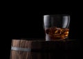 Glass of whiskey with ice cubes on top of wooden barrel. Cognac brandy drink Royalty Free Stock Photo