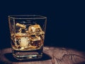 Glass of whiskey with ice cubes on wood table, warm atmosphere, time of relax with whisky Royalty Free Stock Photo