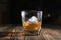 Glass of whiskey with ice cubes on a wooden table. An old tabletop with light and a glass of strong drink. Royalty Free Stock Photo