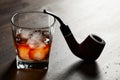 Glass of whiskey with ice and old pipe Royalty Free Stock Photo