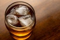 Glass of whiskey with ice on wooden background. Bourbon on dark wood table. Alcohol brown drink with bubbles. Cooled rum, top view Royalty Free Stock Photo