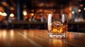 Glass of whiskey with ice on wooden table in bar. Blurred background Royalty Free Stock Photo