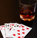 Glass of whiskey and playing cards on a black desk on the wooden table. Angle view, identification cards Royalty Free Stock Photo