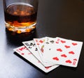 Glass of whiskey and playing cards on a black desk on the wooden table. Angle view, identification cards Royalty Free Stock Photo