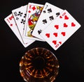 Glass of whiskey and playing cards on a black desk on the wooden table. Angle view, identification cards Royalty Free Stock Photo