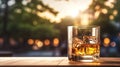 The glass of whiskey on the rock, on the table with a blurred garden background in the golden light afternoon Royalty Free Stock Photo