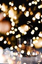 Glass of whiskey with ice on the table with festive holiday bokeh Royalty Free Stock Photo